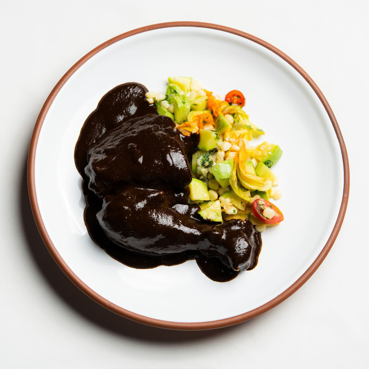 Mole Negro sauce over chicken with a fresh salad.